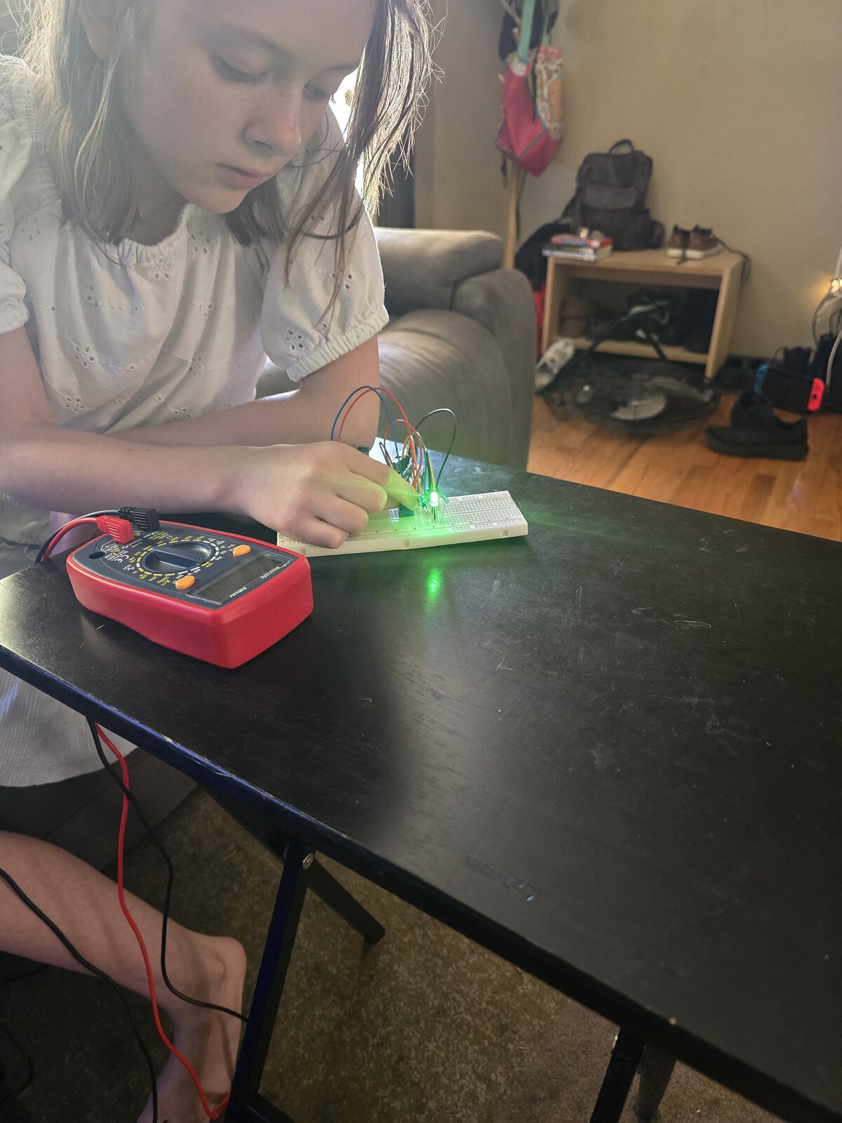 pixie_technologist checking a lit LED on a breadboard with a multimeter