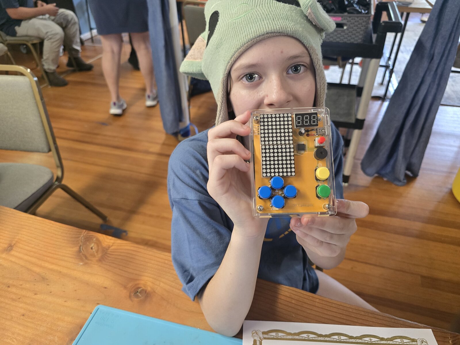 pixie_technologist holding her finished soldered device with LED matrix display and colored buttons